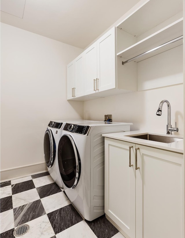 laundry area featuring washing machine and dryer, a sink, baseboards, cabinet space, and light floors