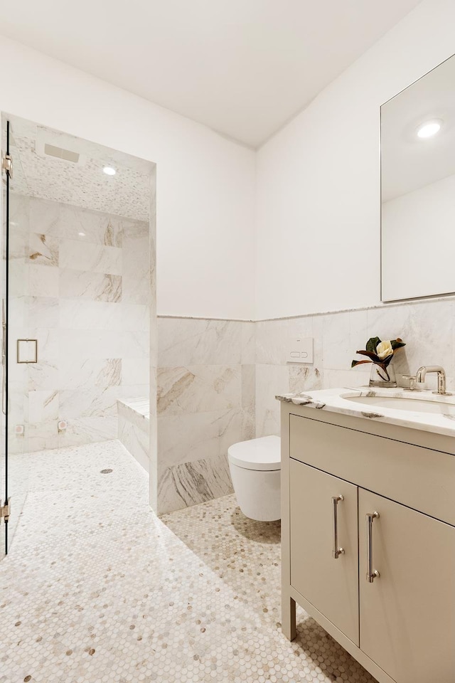 bathroom featuring toilet, vanity, tile walls, a shower stall, and tile patterned floors