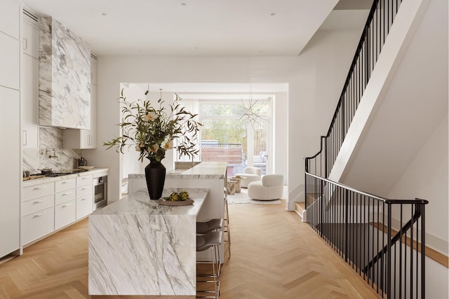 kitchen with a breakfast bar, light countertops, white cabinetry, stainless steel oven, and modern cabinets