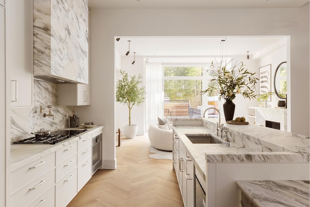 kitchen featuring light stone counters, white cabinetry, decorative backsplash, and a sink