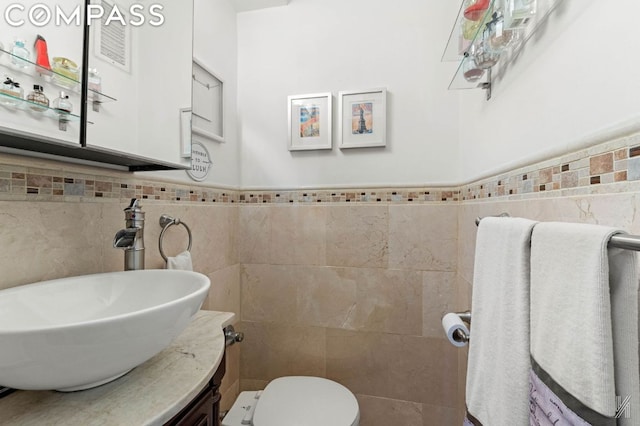 bathroom with toilet, tile walls, and vanity