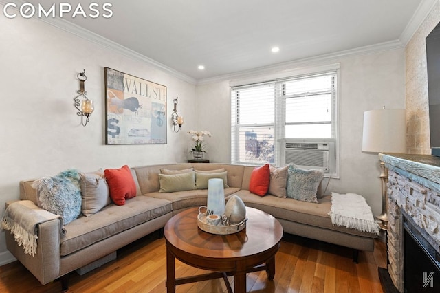 living room with hardwood / wood-style floors, cooling unit, crown molding, and a stone fireplace