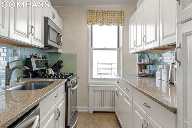 kitchen with light tile patterned flooring, stainless steel appliances, white cabinetry, and sink