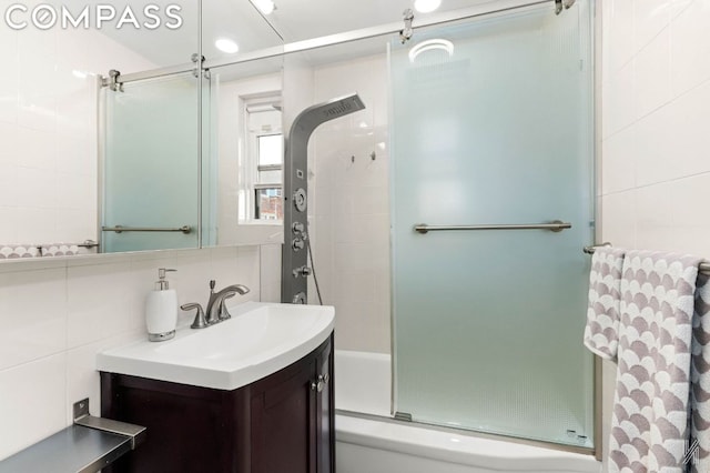 bathroom with decorative backsplash, tile walls, shower / bath combination with glass door, and vanity