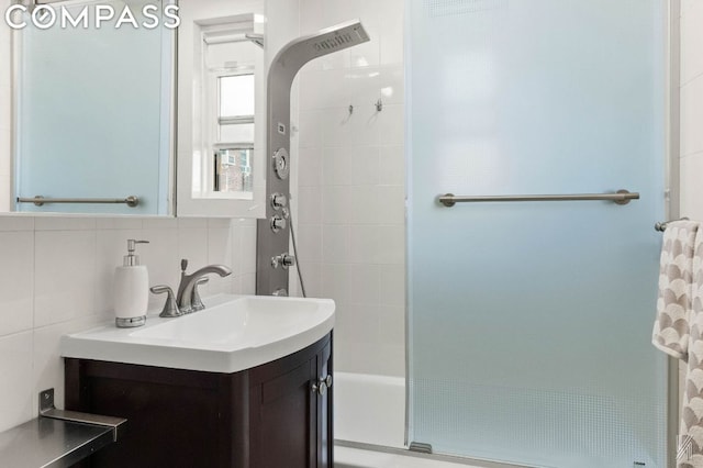 bathroom featuring backsplash, tiled shower, vanity, and tile walls