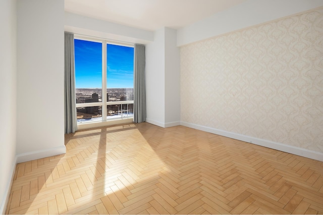 empty room featuring baseboards and wallpapered walls