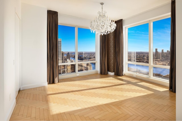 interior space featuring baseboards, a notable chandelier, a city view, and a healthy amount of sunlight