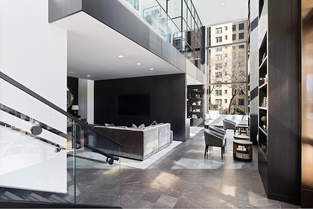 living room with marble finish floor, a towering ceiling, and stairs