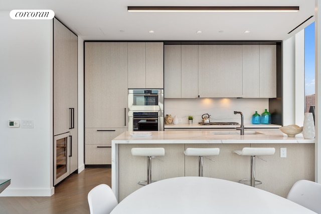 kitchen with visible vents, stainless steel double oven, modern cabinets, beverage cooler, and a kitchen breakfast bar