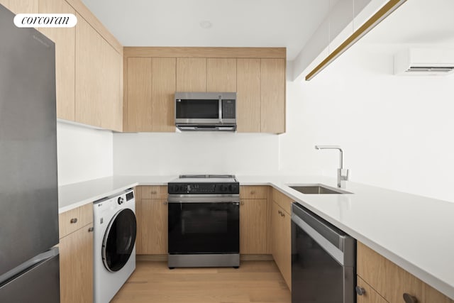 kitchen with stainless steel appliances, washer / dryer, sink, and light brown cabinets