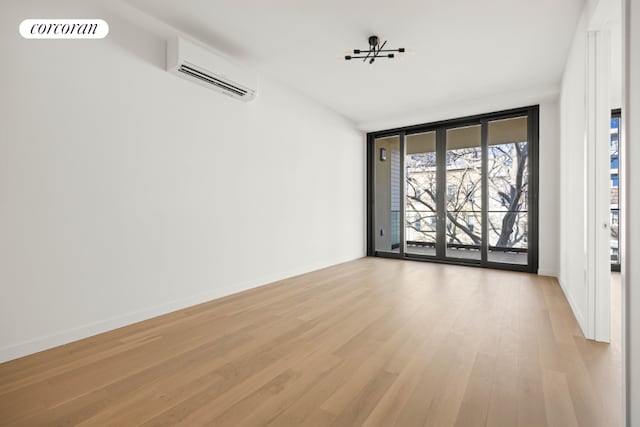 unfurnished room featuring floor to ceiling windows, a wall mounted AC, and light wood-type flooring