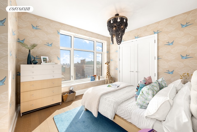 bedroom featuring a closet, wallpapered walls, and wood finished floors