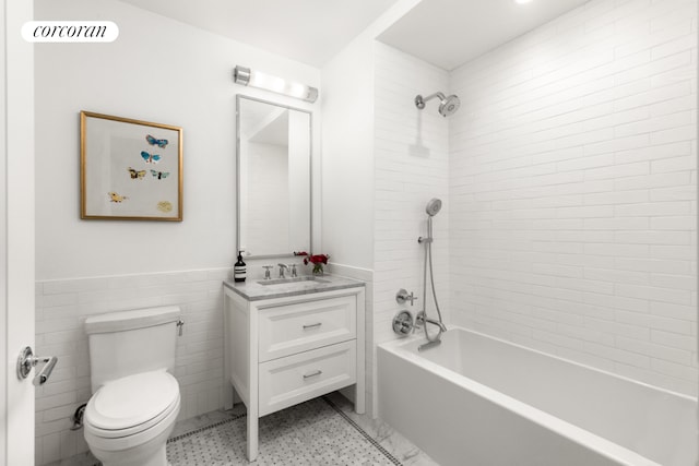 full bathroom with visible vents, shower / bathtub combination, toilet, vanity, and wainscoting