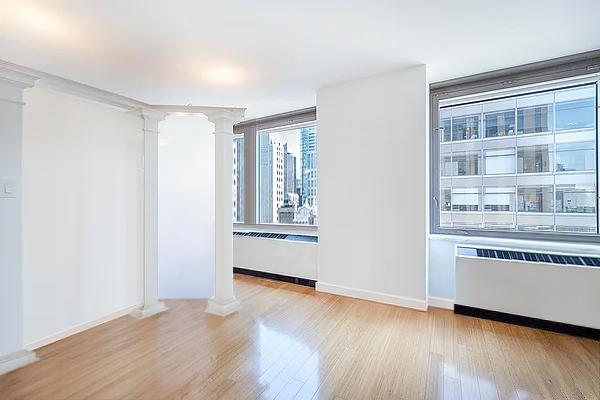 spare room with ornate columns, crown molding, radiator, and light wood-type flooring