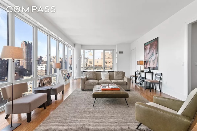 living room with baseboards, a city view, and wood finished floors