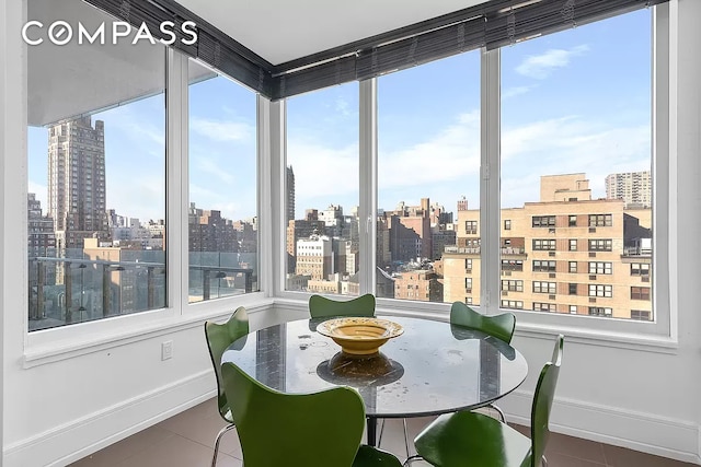 dining room with baseboards, a view of city, and tile patterned flooring