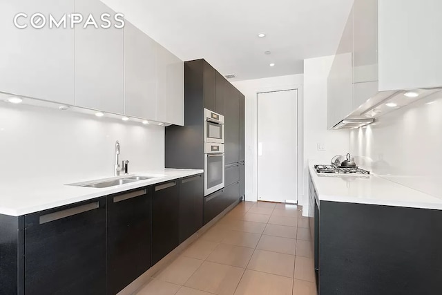 kitchen with a sink, light countertops, stainless steel appliances, modern cabinets, and dark cabinets