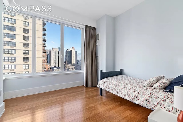 bedroom featuring baseboards, a city view, and wood finished floors