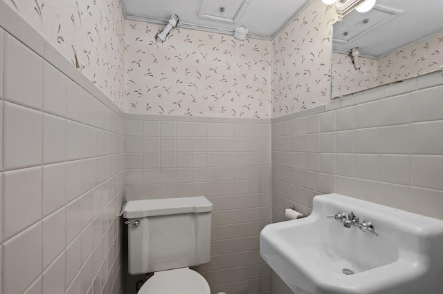 283 Bay 14th St, New York City, NY 11214 - bathroom featuring wallpapered walls, tile walls, toilet, a sink, and a wainscoted wall