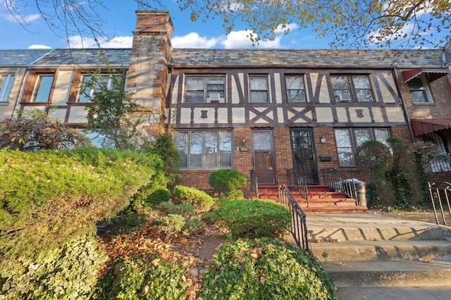 tudor home featuring brick siding and a chimney