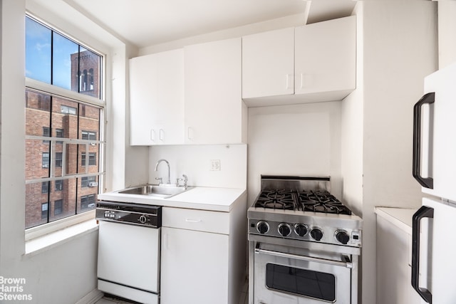 kitchen with white appliances, light countertops, a sink, and white cabinets