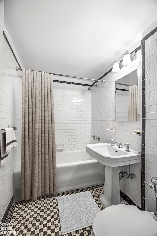 bathroom with toilet, shower / bath combo with shower curtain, and tile walls