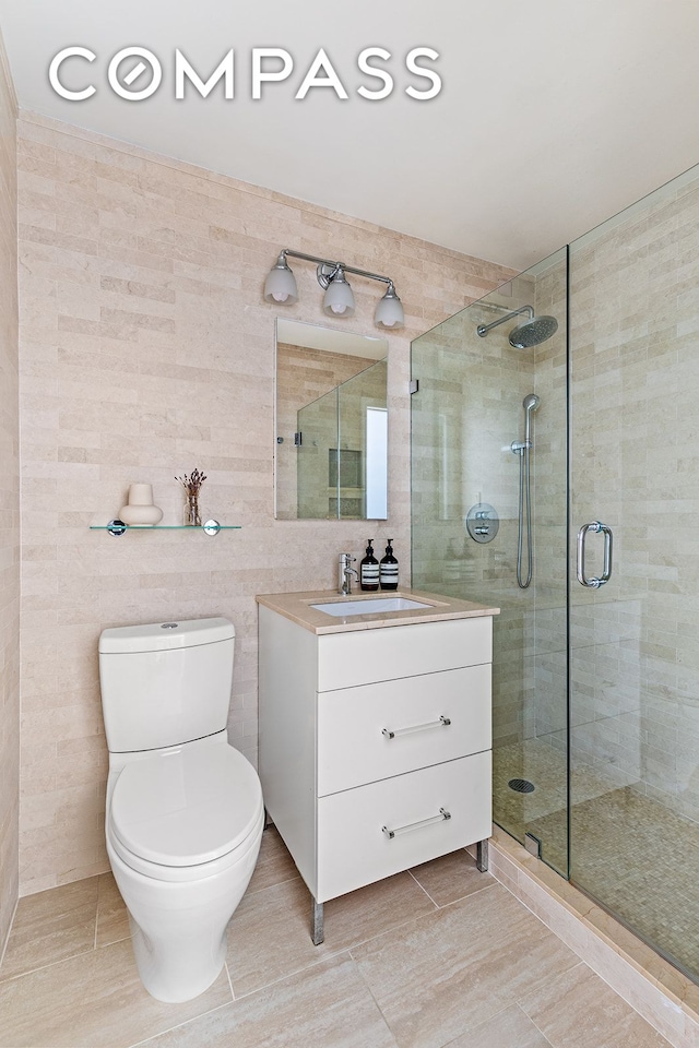 bathroom with a stall shower, toilet, tile walls, and vanity