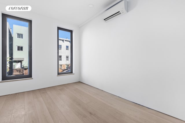 spare room featuring a wall mounted air conditioner, visible vents, and light wood finished floors