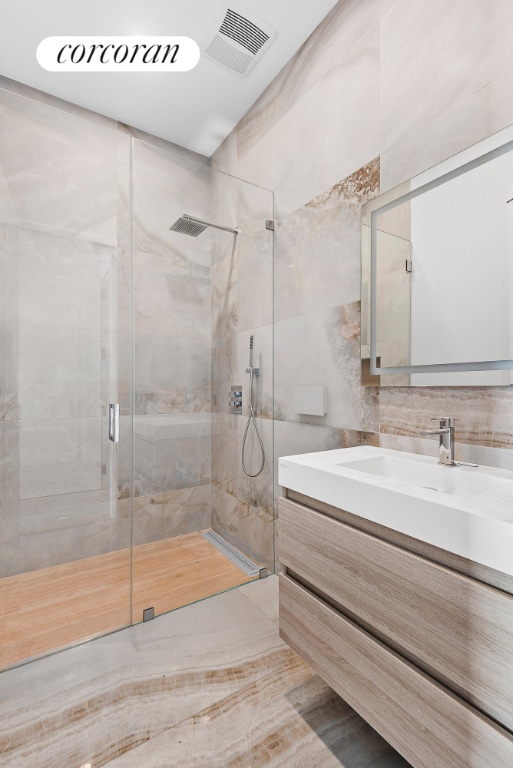 full bathroom with a stall shower, visible vents, tile walls, vanity, and backsplash