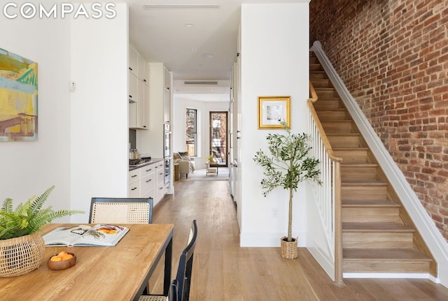 interior space with brick wall and light hardwood / wood-style flooring