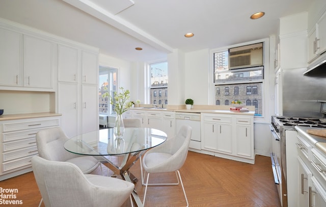 kitchen featuring light parquet floors, gas range, white cabinets, and white dishwasher