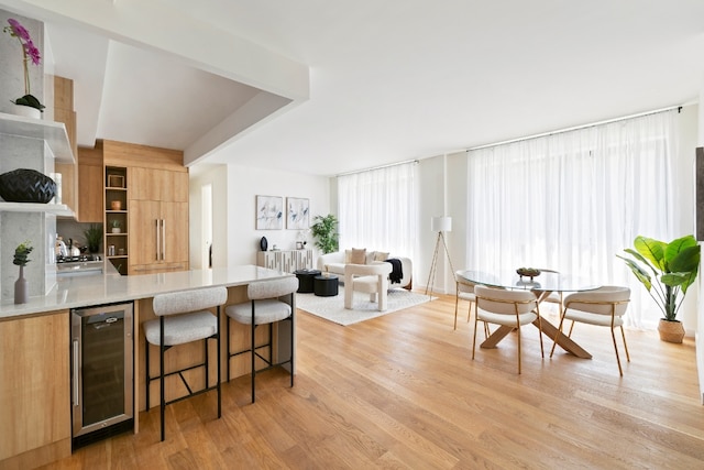 kitchen featuring a kitchen bar, wine cooler, and light hardwood / wood-style floors