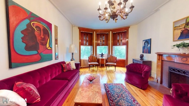 living room with a tiled fireplace, a notable chandelier, and wood-type flooring