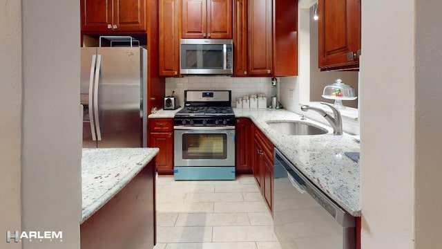 kitchen featuring appliances with stainless steel finishes, light stone countertops, sink, and backsplash