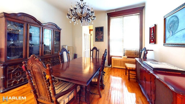 dining space featuring light wood-type flooring, radiator, and a notable chandelier