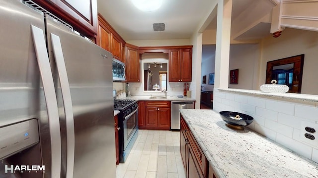 kitchen with visible vents, decorative backsplash, light stone countertops, stainless steel appliances, and a sink