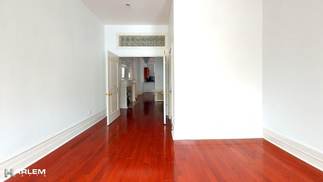 hallway featuring dark wood-style flooring and baseboards