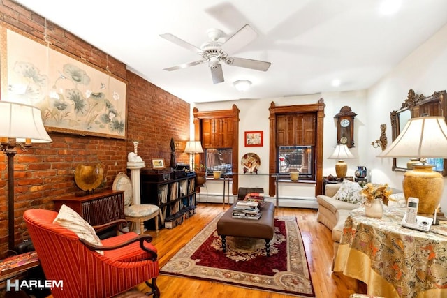 living room with a ceiling fan, a baseboard radiator, brick wall, and wood finished floors