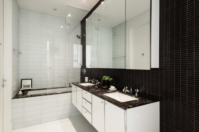 bathroom with tile walls, a tile shower, decorative backsplash, double vanity, and a bath