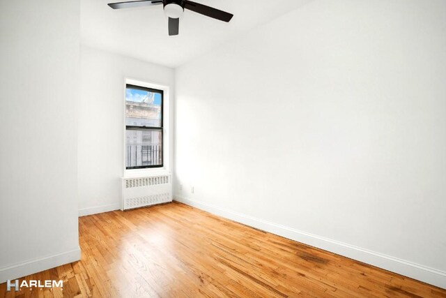 unfurnished room with ceiling fan, radiator, and wood-type flooring