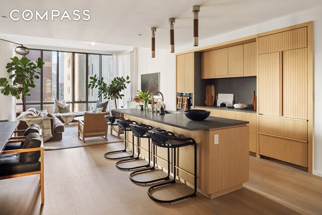 kitchen featuring light wood-style flooring, a kitchen island, a kitchen breakfast bar, cream cabinetry, and dark countertops