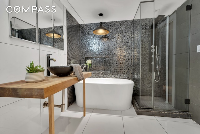 bathroom featuring tile patterned flooring, a sink, tile walls, a soaking tub, and a stall shower