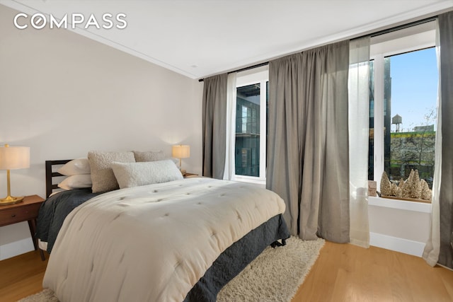 bedroom with crown molding, light wood finished floors, and baseboards