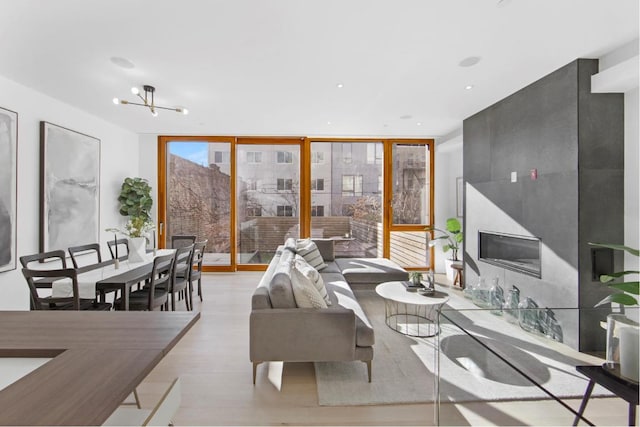 living room with a notable chandelier, a premium fireplace, light hardwood / wood-style flooring, and expansive windows