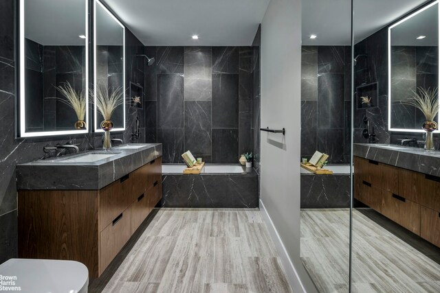 bathroom featuring tile walls, a tub to relax in, and vanity