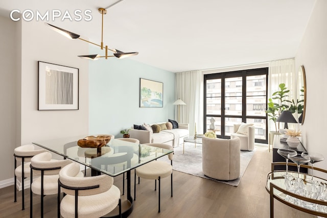 living area with expansive windows, baseboards, wood finished floors, and a chandelier