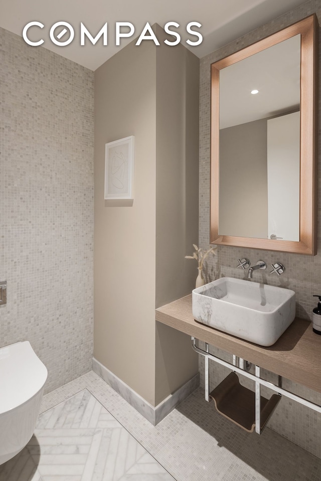 half bathroom with toilet, tile walls, and a sink