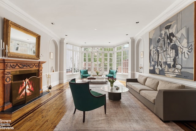 living room featuring wood finished floors, crown molding, and a lit fireplace