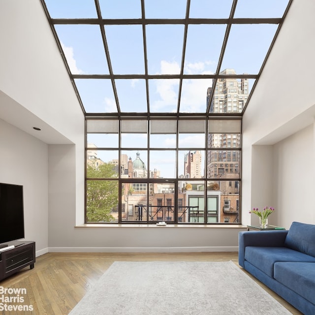 living room with a city view, a towering ceiling, wood finished floors, and baseboards
