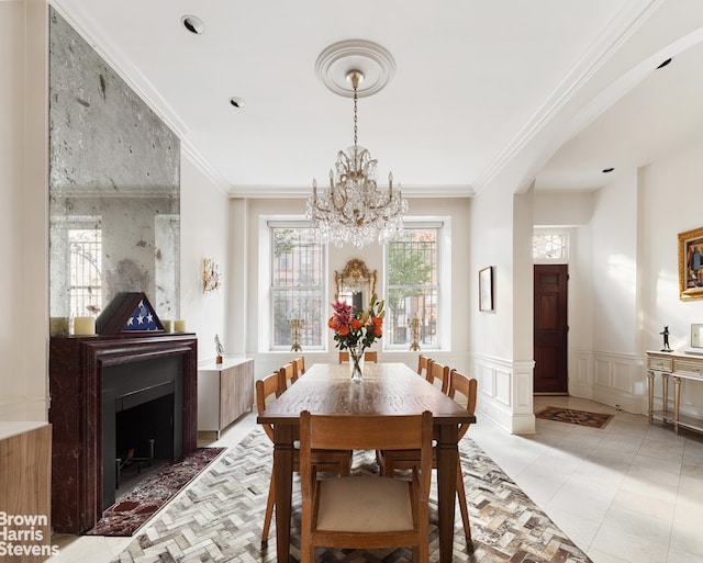 dining area with a large fireplace, a chandelier, and ornamental molding